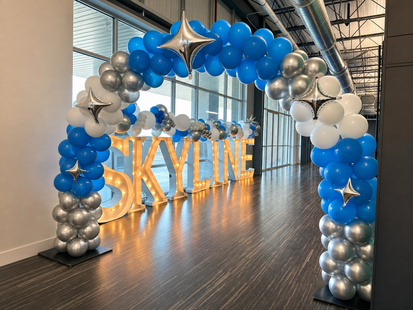 Blue and silver balloon arch at a skyline entrance
